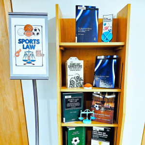 a sign says book display sports law to the left of a small shelf of books about sports law