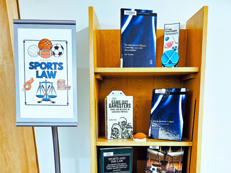 a sign says book display sports law to the left of a small shelf of books about sports law