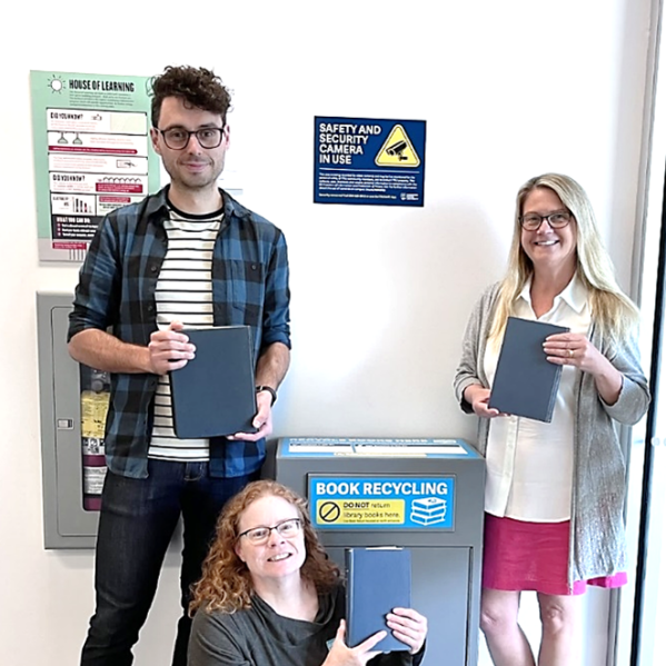 Book recycling box with library staff standing around it holding books