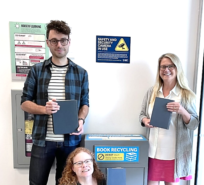 Book recycling box with library staff standing around it holding books