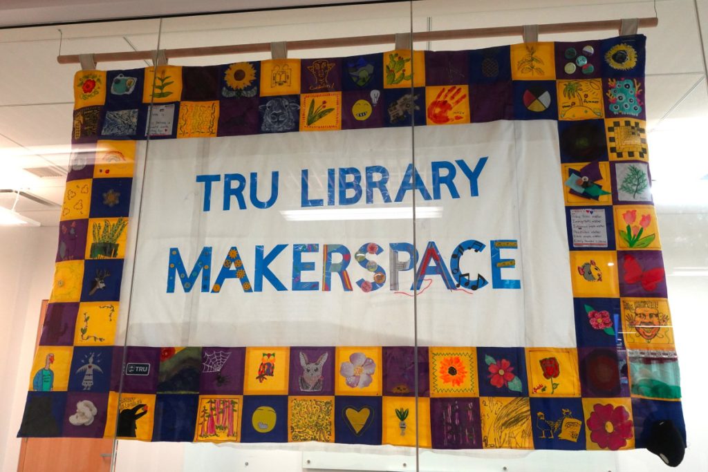 Close-up of the collaborative banner which says TRU Library Makerspace in the middle and squares depicting a wide variety of images designed and donated by TRU community members.