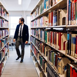 student in a suit walking through the book shelves in the law library at TRU.
